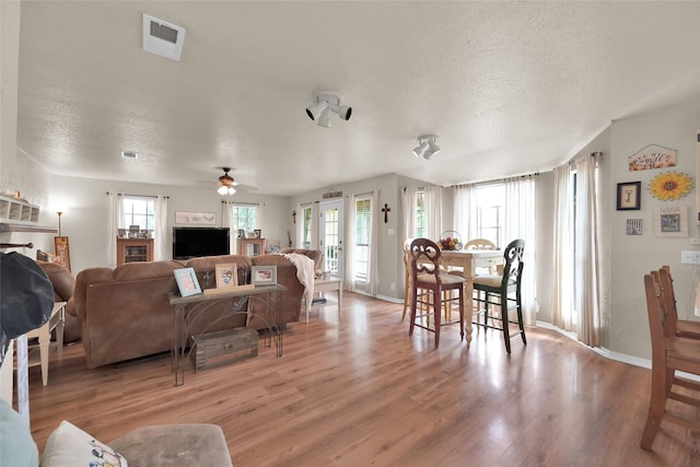 living room with ceiling fan, a textured ceiling, and light wood-type flooring