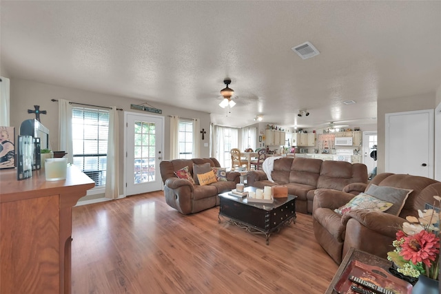 living room featuring ceiling fan, hardwood / wood-style floors, and a textured ceiling