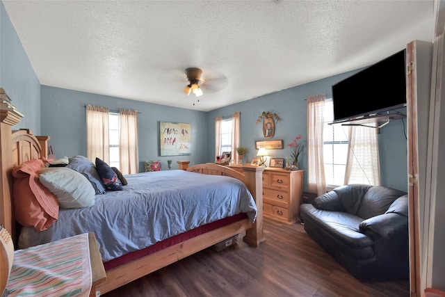 bedroom featuring dark wood-type flooring, ceiling fan, multiple windows, and a textured ceiling