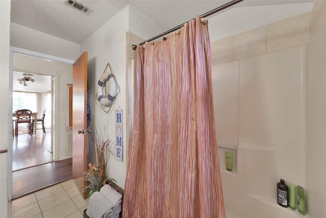 bathroom featuring shower / bath combination with curtain, tile patterned floors, and a textured ceiling