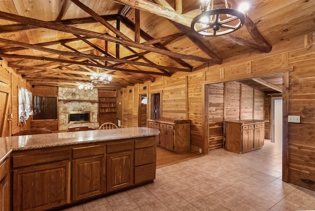 kitchen with vaulted ceiling with beams, wooden ceiling, wood walls, a fireplace, and open floor plan