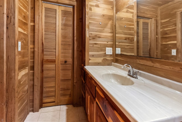 bathroom featuring tile patterned flooring, a closet, wood walls, and vanity