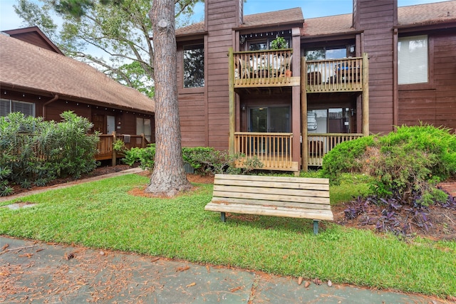 back of property with a balcony and a lawn