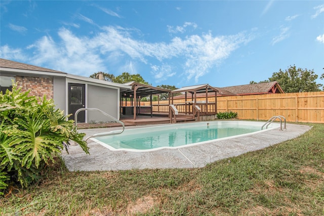 view of pool with a wooden deck and a lawn