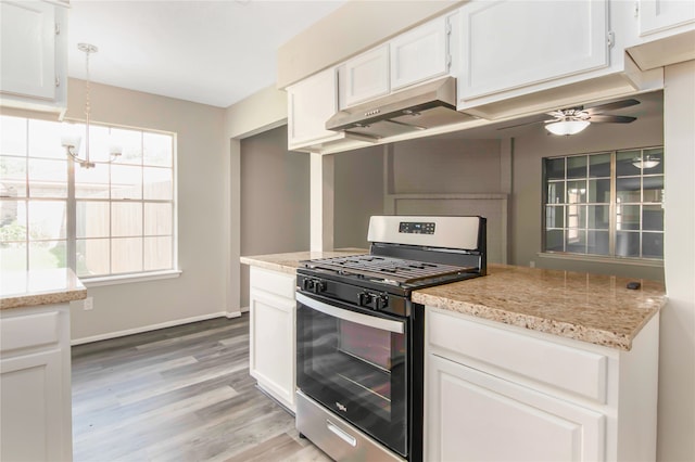 kitchen with stainless steel gas range, hardwood / wood-style floors, ceiling fan with notable chandelier, light stone countertops, and white cabinets