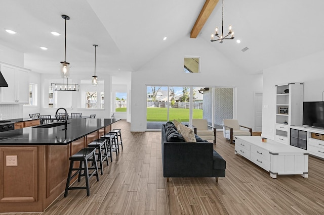 living room with beamed ceiling, plenty of natural light, a chandelier, and light hardwood / wood-style floors