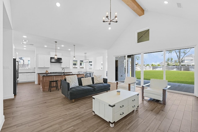 living room featuring beamed ceiling, a chandelier, high vaulted ceiling, and light wood-type flooring