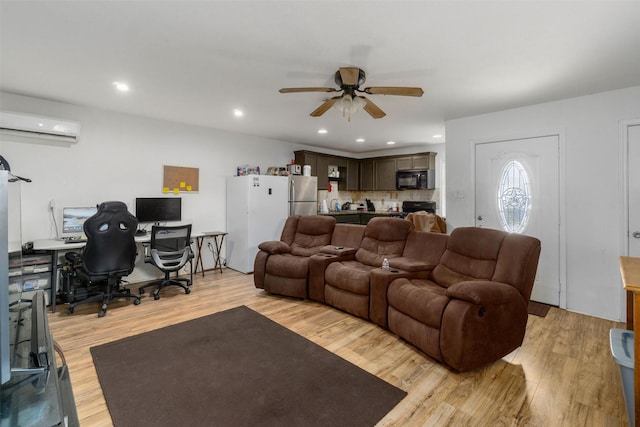 living room featuring light hardwood / wood-style floors, an AC wall unit, and ceiling fan