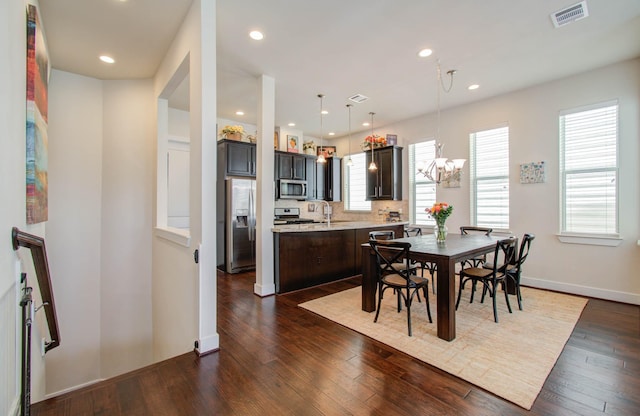 dining space with dark hardwood / wood-style floors, an inviting chandelier, and sink