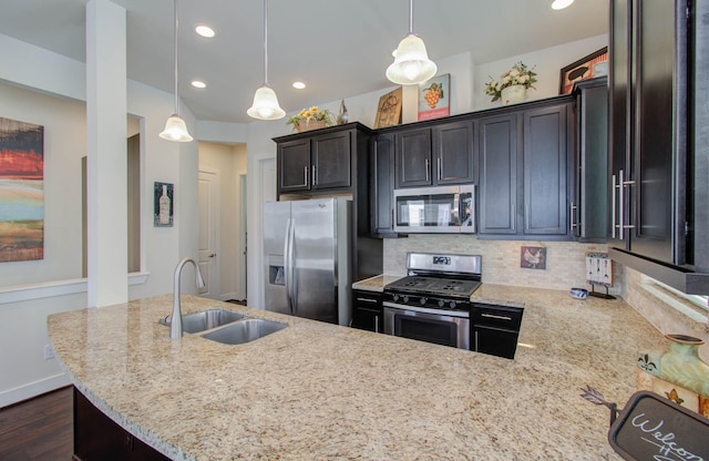 kitchen featuring decorative backsplash, appliances with stainless steel finishes, dark wood-type flooring, sink, and hanging light fixtures