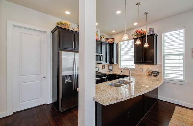 kitchen featuring pendant lighting, backsplash, sink, appliances with stainless steel finishes, and dark hardwood / wood-style flooring