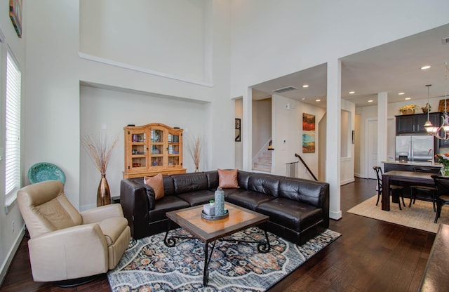 living room featuring dark wood-type flooring and a high ceiling