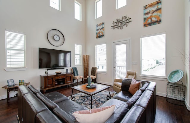 living room with a high ceiling, a wealth of natural light, and dark wood-type flooring