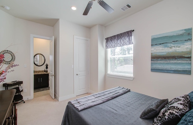 bedroom with ceiling fan, light colored carpet, connected bathroom, and a closet