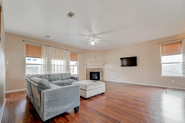 living room featuring a tile fireplace, hardwood / wood-style flooring, and ceiling fan