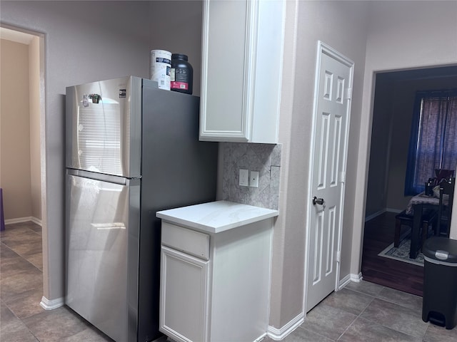 kitchen featuring white cabinetry, decorative backsplash, stainless steel refrigerator, and light tile patterned floors