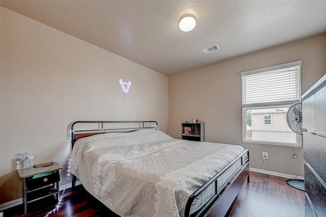 bedroom featuring a textured ceiling and dark hardwood / wood-style flooring