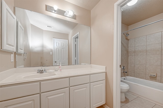 full bathroom featuring tile patterned flooring, a textured ceiling, tiled shower / bath combo, toilet, and vanity