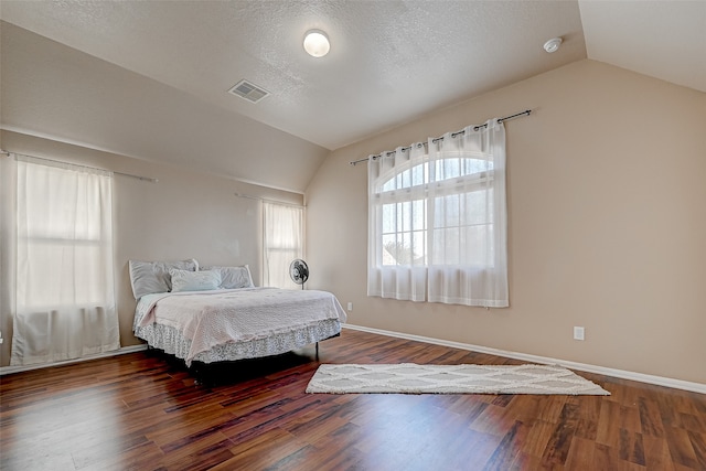 bedroom with lofted ceiling, hardwood / wood-style floors, and a textured ceiling