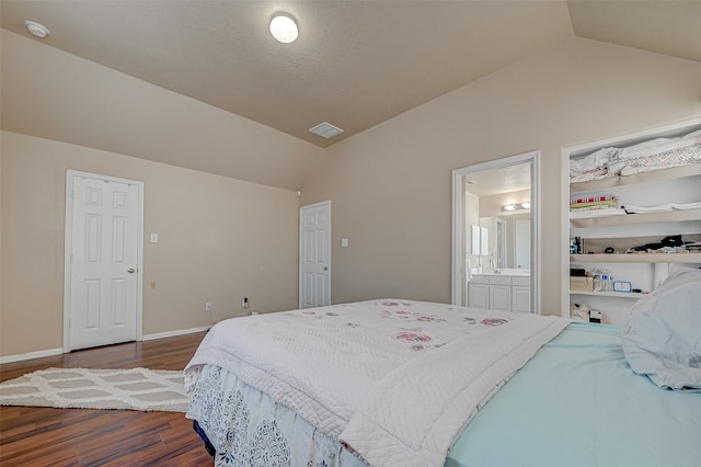 bedroom with ensuite bath, lofted ceiling, and hardwood / wood-style flooring