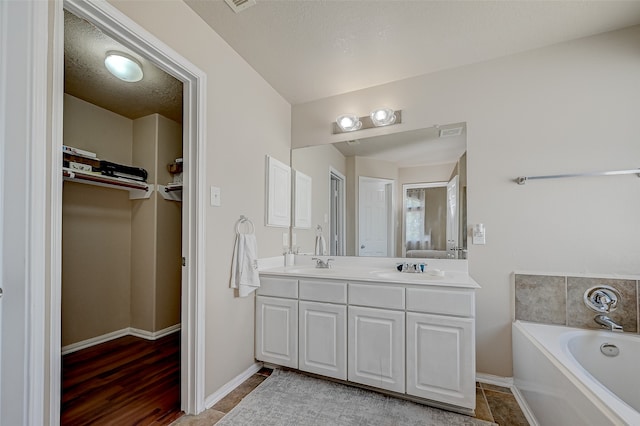 bathroom with tile patterned floors, a washtub, a textured ceiling, and double vanity