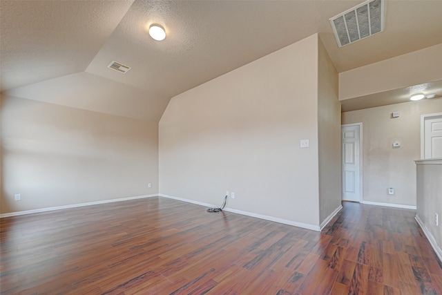 spare room with hardwood / wood-style floors, a textured ceiling, and vaulted ceiling