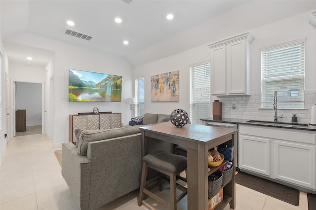 kitchen featuring vaulted ceiling, decorative backsplash, sink, and white cabinets