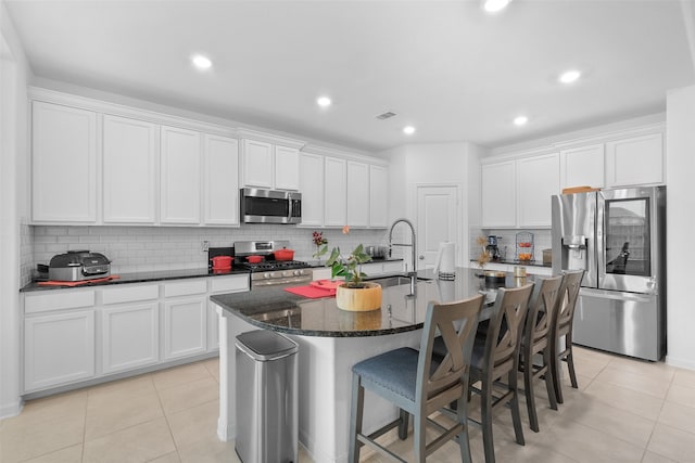 kitchen featuring appliances with stainless steel finishes, white cabinetry, and an island with sink