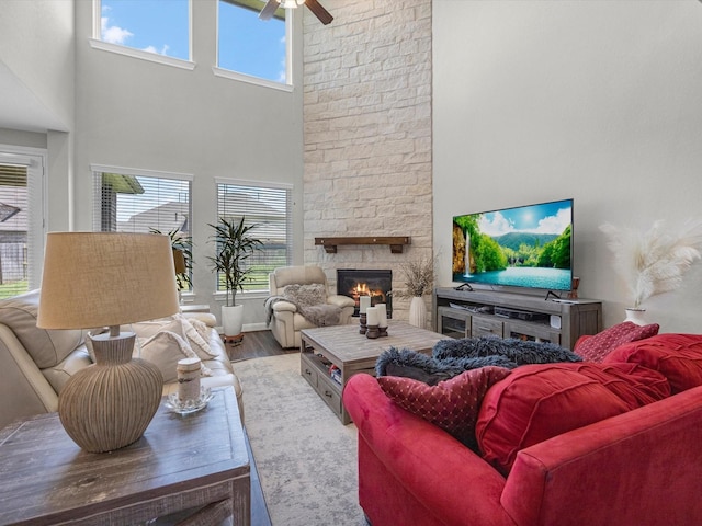 living room featuring a fireplace, hardwood / wood-style floors, a towering ceiling, and ceiling fan