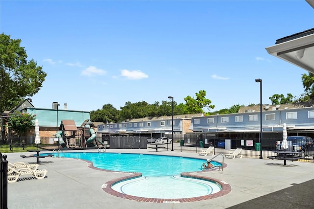 view of swimming pool with a playground and a patio area