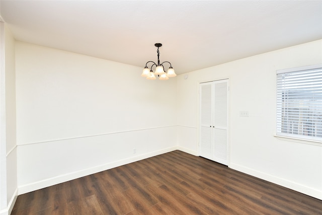 unfurnished room with dark wood-type flooring and a notable chandelier