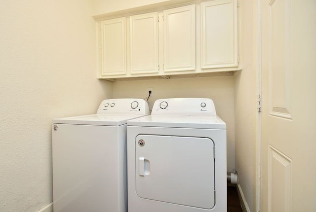 clothes washing area with washer and clothes dryer and cabinets