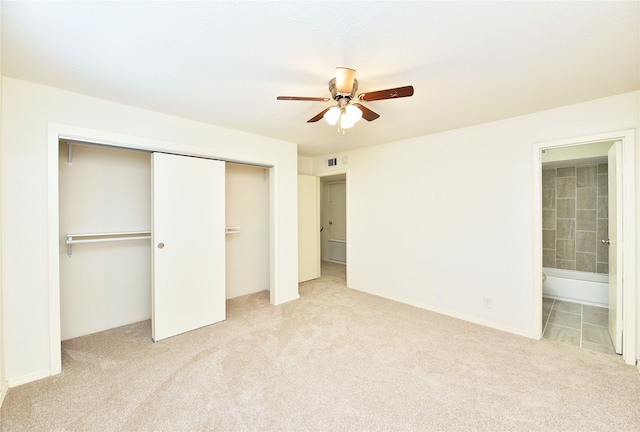 unfurnished bedroom with light carpet, a closet, ceiling fan, and ensuite bathroom