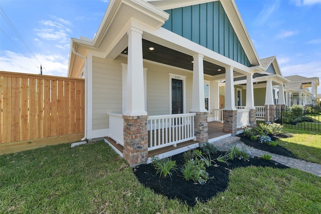 view of exterior entry featuring a yard and covered porch