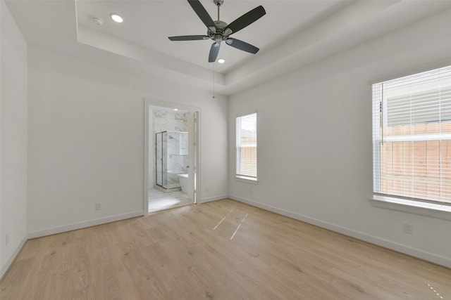 unfurnished bedroom featuring ceiling fan, light hardwood / wood-style flooring, connected bathroom, and multiple windows