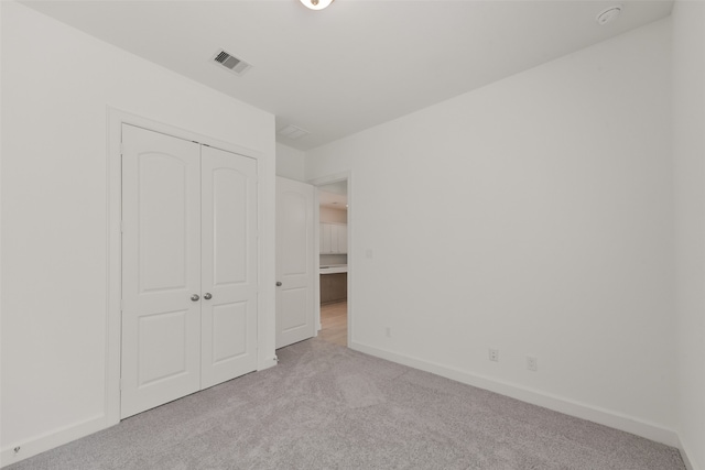 unfurnished bedroom featuring light carpet and a closet