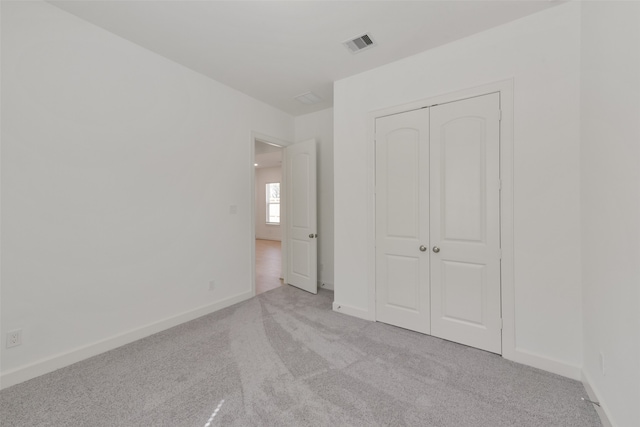 unfurnished bedroom with a closet and light colored carpet