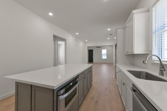 kitchen with appliances with stainless steel finishes, a kitchen island, sink, and white cabinets