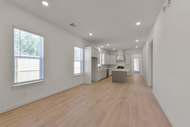 kitchen with custom exhaust hood, light hardwood / wood-style flooring, a healthy amount of sunlight, and a center island