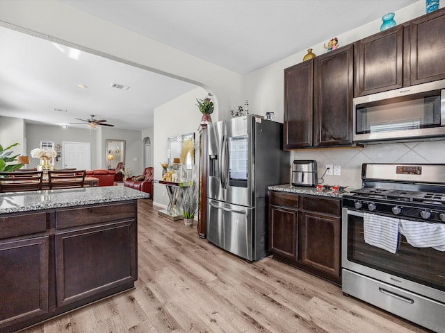 kitchen featuring light hardwood / wood-style flooring, backsplash, ceiling fan, stainless steel appliances, and light stone countertops