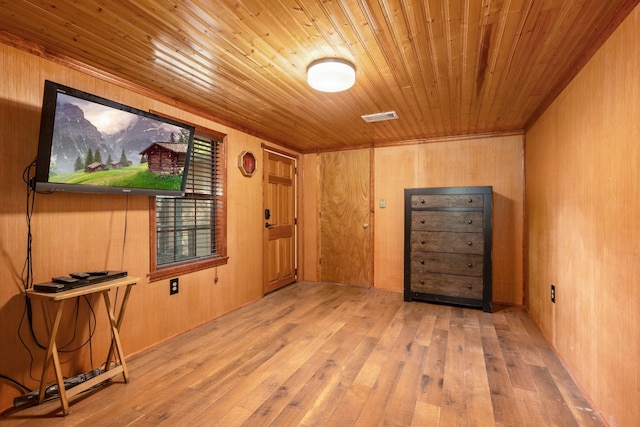 spare room featuring wood ceiling, light wood-type flooring, and wooden walls