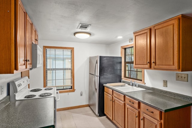 kitchen featuring a textured ceiling, sink, and white appliances