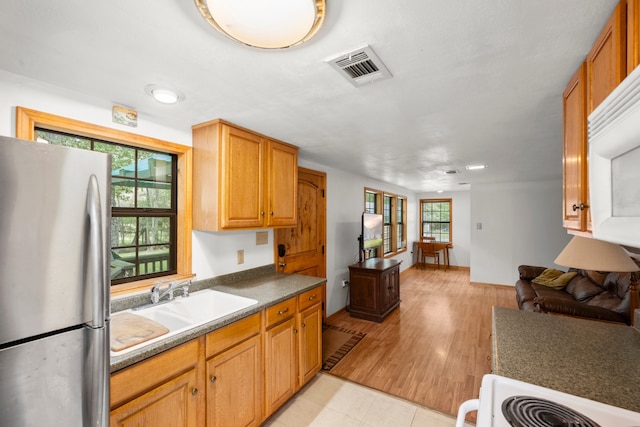 kitchen featuring range, light wood-type flooring, stainless steel refrigerator, and sink