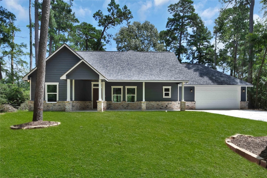 view of front of home featuring brick siding, a shingled roof, a front yard, a garage, and driveway