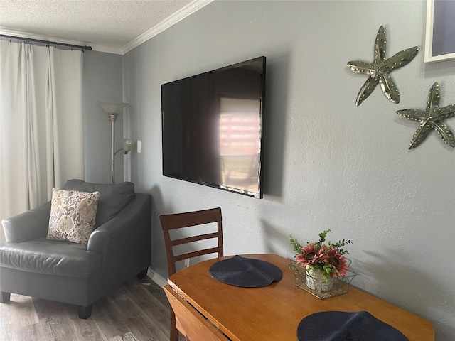 dining space with a textured ceiling, wood-type flooring, and ornamental molding