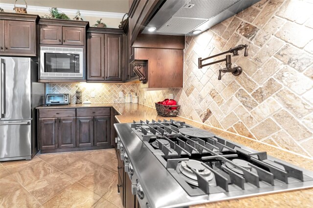 kitchen with built in microwave, tasteful backsplash, stovetop, stainless steel fridge, and dark brown cabinetry