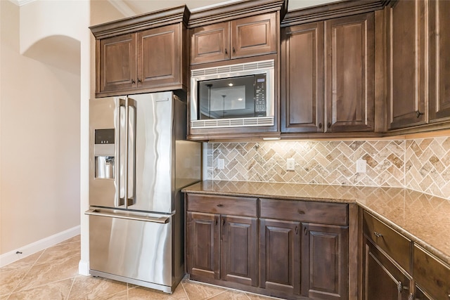 203 Gaillardia Ct, Pinehurst, TX 77362 - kitchen featuring stainless steel refrigerator with ice dispenser, built in microwave, backsplash, stone counters, and baseboards