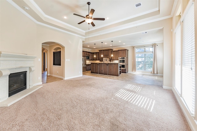 203 Gaillardia Ct, Pinehurst, TX 77362 - unfurnished living room featuring a raised ceiling, ornamental molding, light colored carpet, a premium fireplace, and ceiling fan