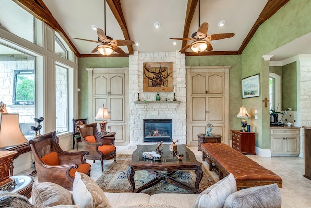 living room with a stone fireplace, ceiling fan, beamed ceiling, and high vaulted ceiling