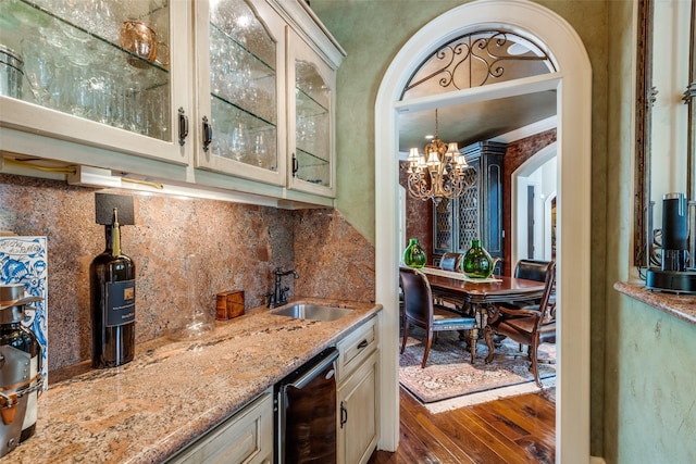 bar featuring light stone countertops, sink, a chandelier, and wood-type flooring